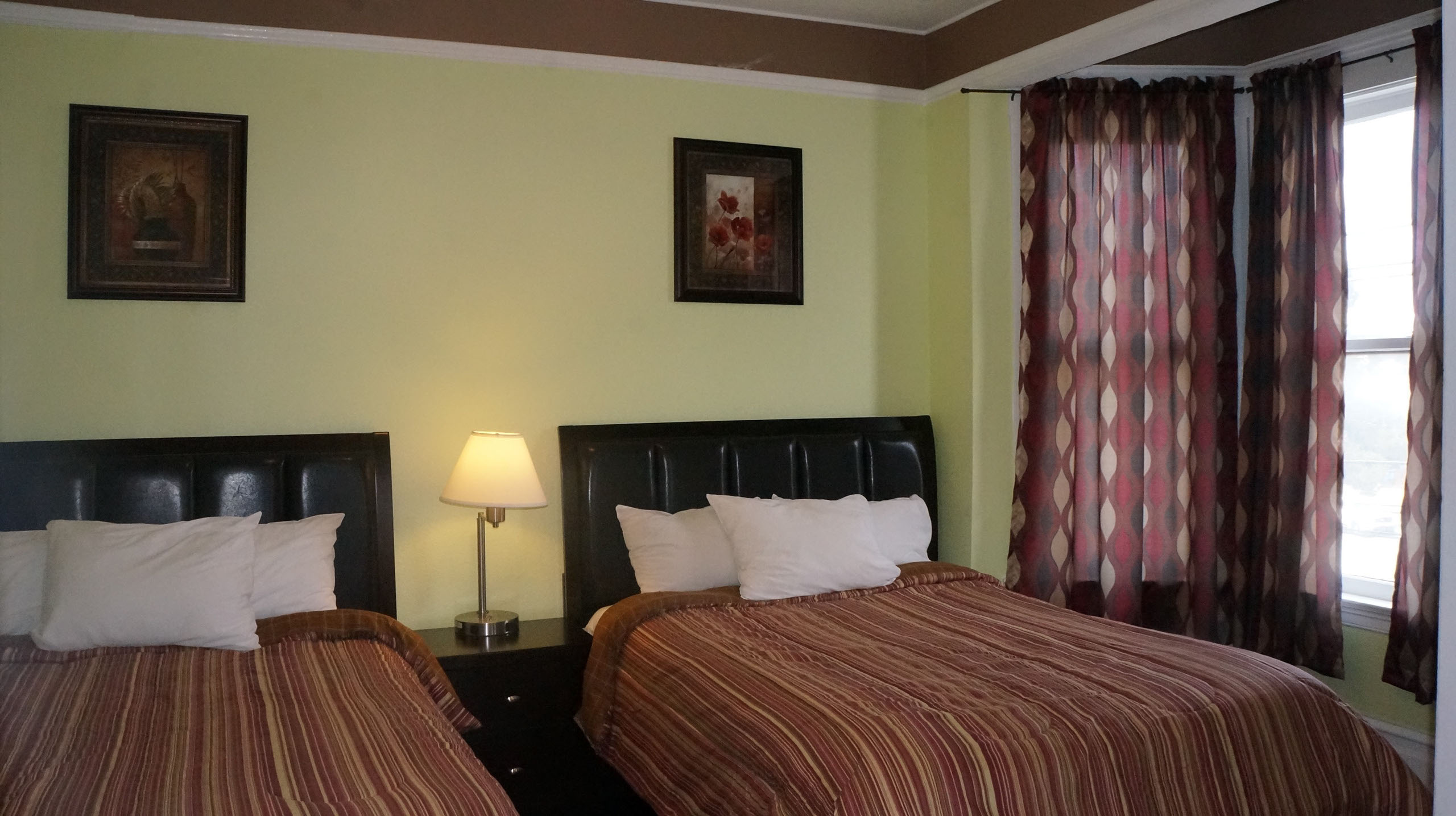 A hotel room with two beds, a nightstand, and a window.