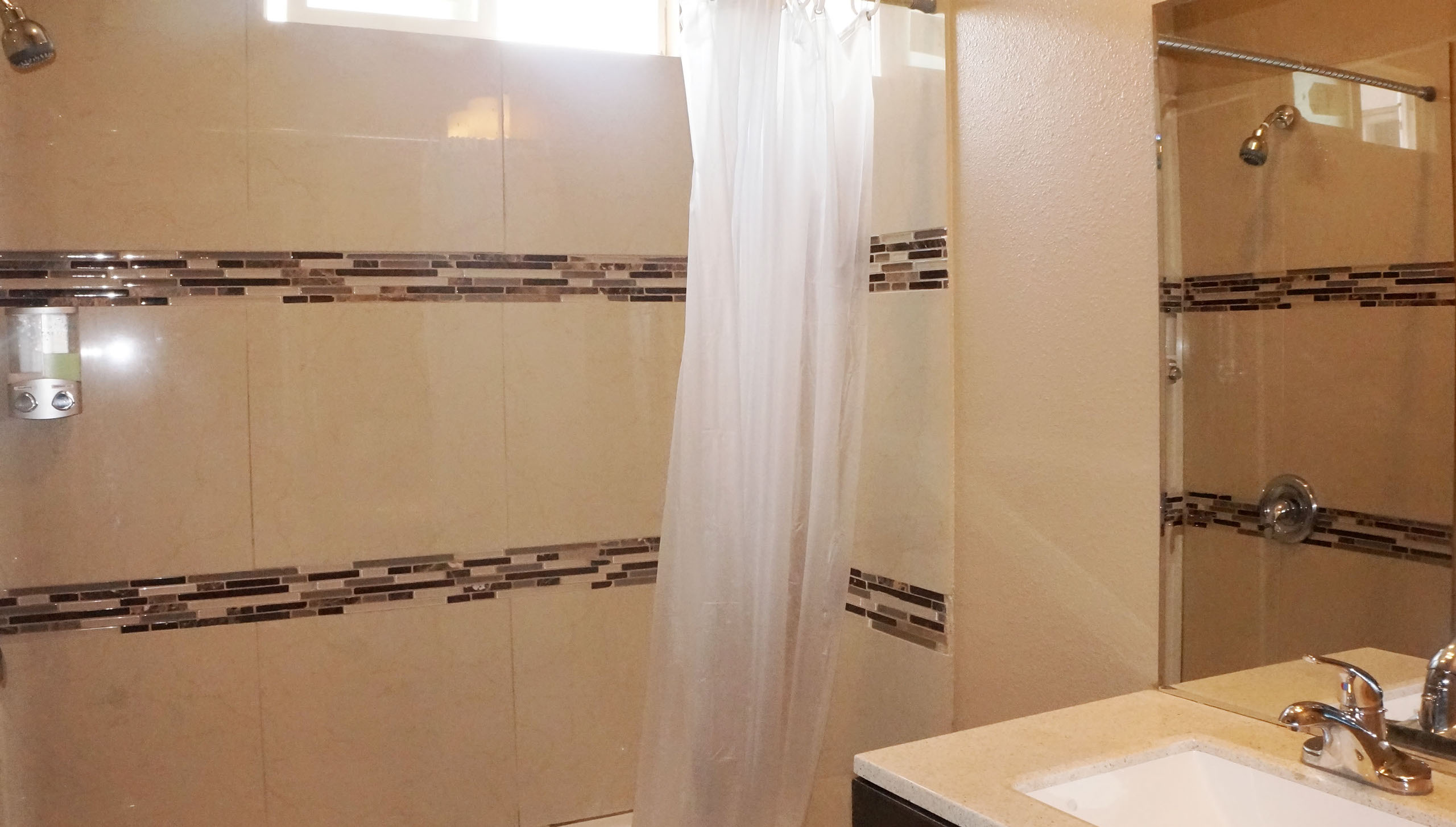 A bathroom with a shower, sink, and mirror
