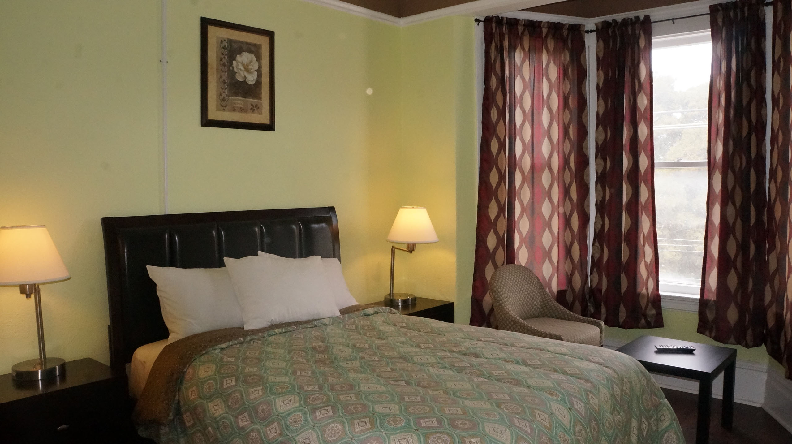 A hotel room with a bed, nightstands, lamps, a chair, and a window