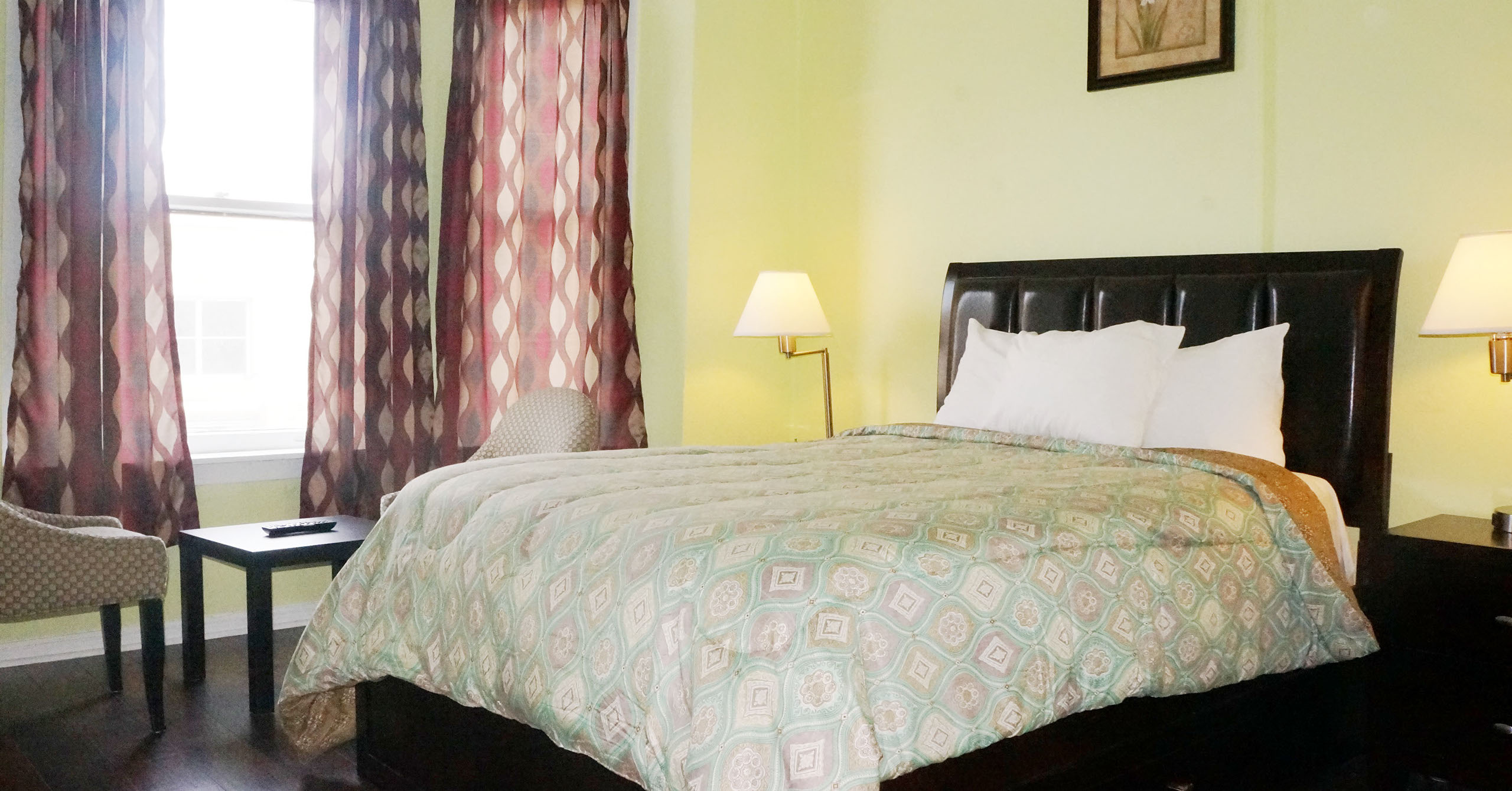 A hotel room with a large bed, two nightstands, and a window with curtains.